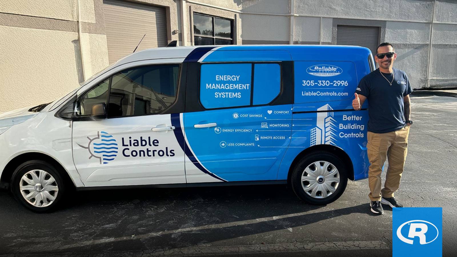 A man wearing sunglasses and a Liable Controls t-shirt stands next to a white and blue company van giving a thumbs-up. 